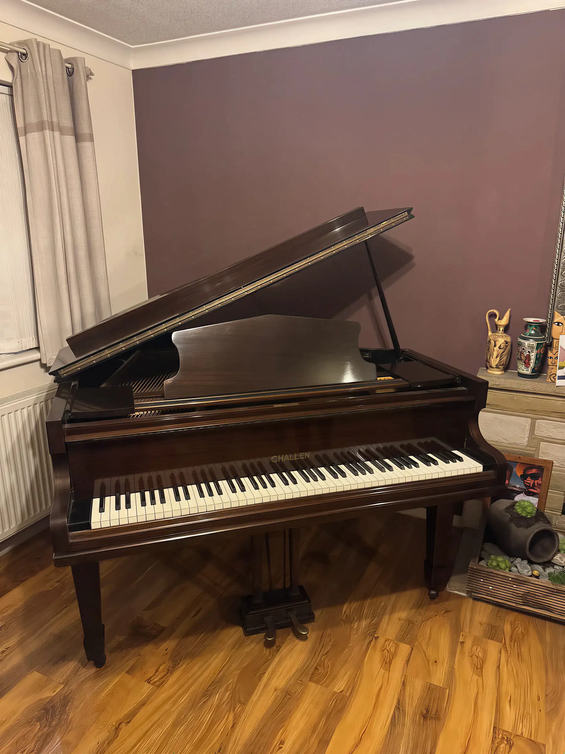 A mahogany Challen baby grand piano with the lid open in a carpeted room