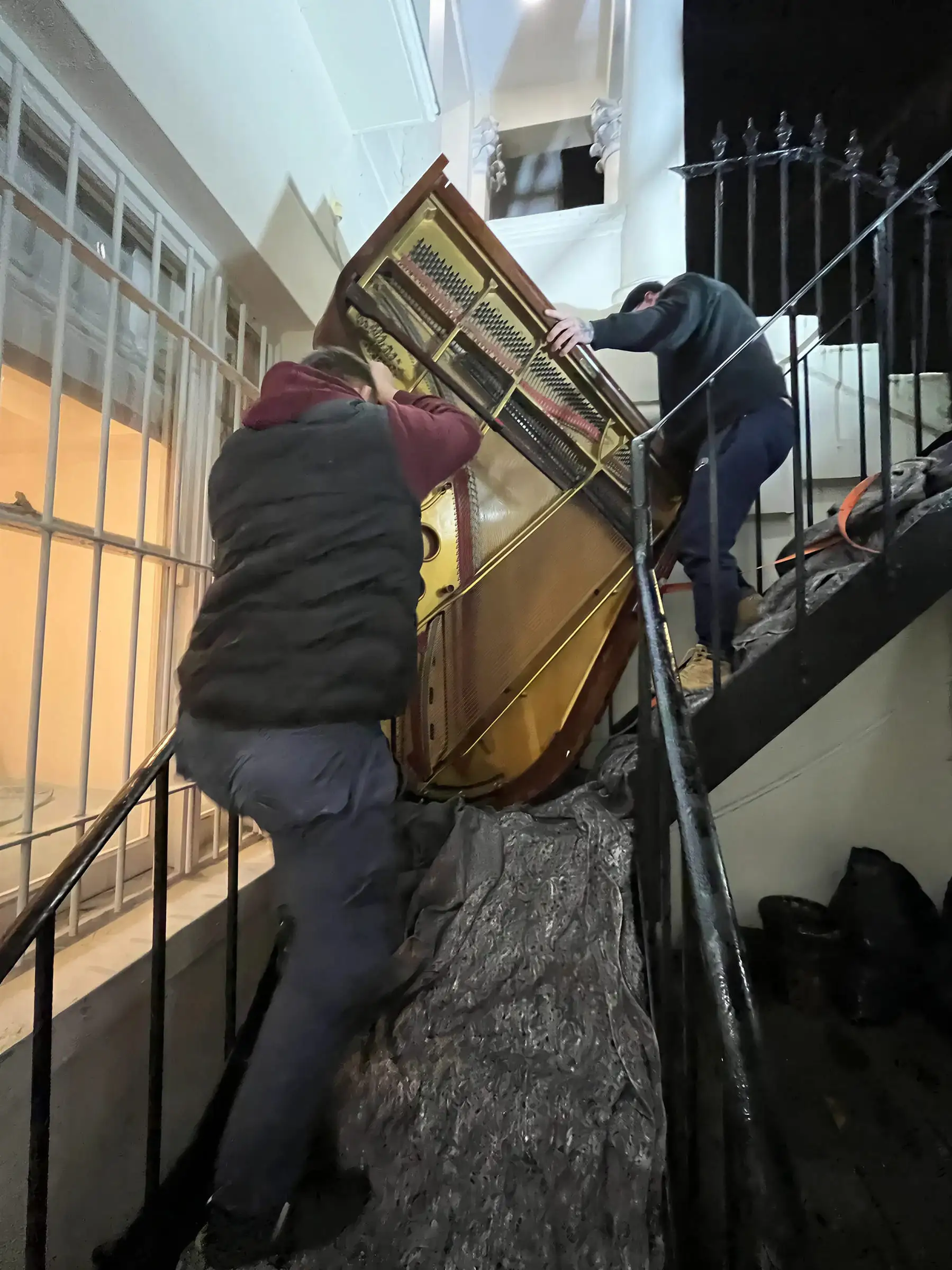 The same baby grand further up the staircase, one mover below it and one above