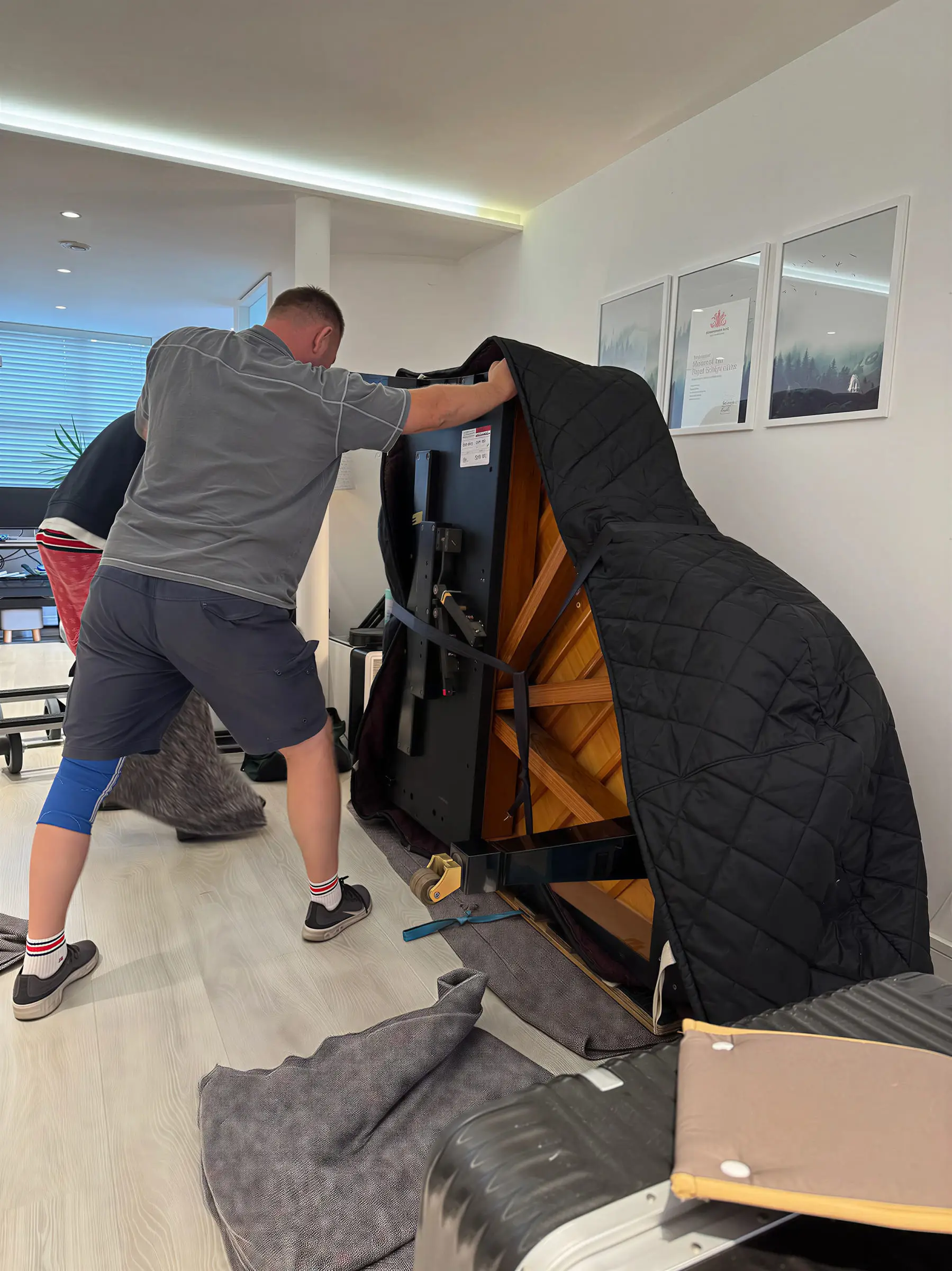 A mover taking down a grand piano onto its side, ready to be collected