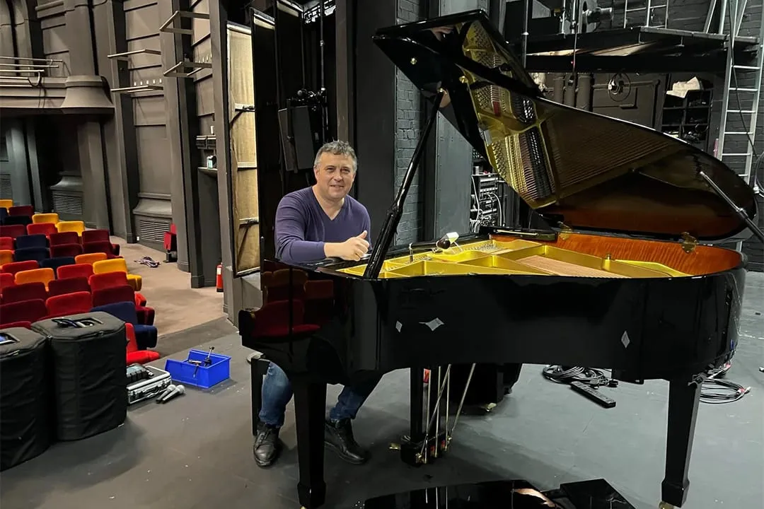 A piano tuner at work beside a freshly delivered piano