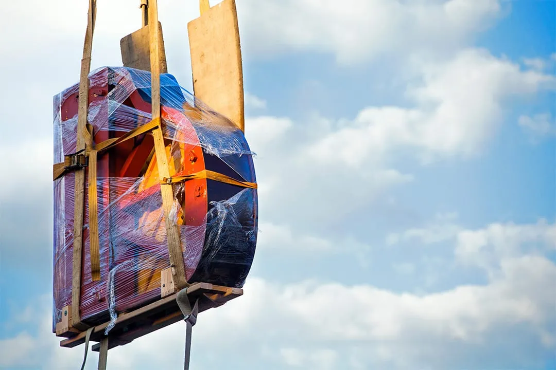 A piano being wheeled on skates towards a waiting van
